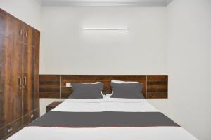 Indirapuram的住宿－Collection O Raksha Inn Near PVR Ansal Plaza Greater Noida，卧室配有白色的床和木制橱柜。