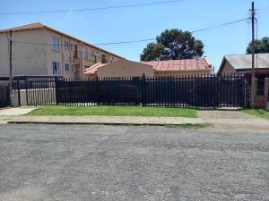 a black wrought iron fence in front of a house at Olivia Pines Guesthouse in Krugersdorp