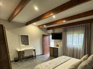 a bedroom with a bed and a desk and a television at De Akker Guest House Louis Trichardt in Louis Trichardt
