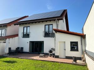 uma casa branca com painéis solares no telhado em furnished & equipped TDY-TLA-TLF House-A - vollständig ausgestattetes Ferienhaus em Bruchmühlbach-Miesau