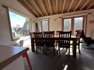 a dining room with a table and chairs and windows at Brindabella Chalet alpine-getaways in Dinner Plain +2 photos