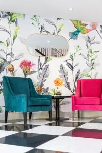twee stoelen en een tafel voor een muur met bloemen bij Protea Hotel by Marriott Franschhoek in Franschhoek