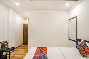 a white bedroom with a bed and a chair at FabHotel Royal Stay in Nagpur
