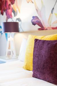 a bed with a purple and yellow pillow on it at Protea Hotel by Marriott Franschhoek in Franschhoek