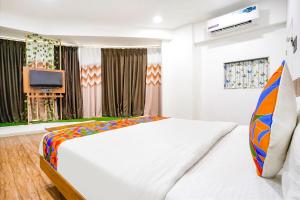 a bedroom with a large white bed and a television at FabHotel 7 Star in Surat