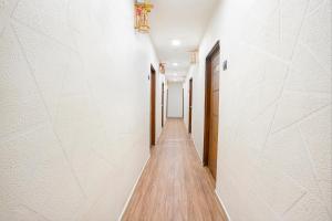 un lungo corridoio con pareti bianche e pavimenti in legno di FabHotel 7 Star a Surat