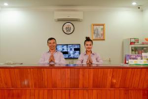 een man en een vrouw die aan een toonbank zitten bij Holiday Hotel in Kampong Speu