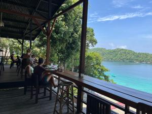 people sitting at a bar on a deck overlooking the water at Olala Bungalows and Restaurant in Sabang