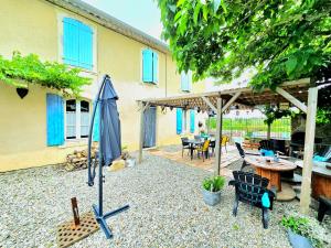 eine Terrasse mit einem Sonnenschirm, einem Tisch und Stühlen in der Unterkunft La Médéenne in Alairac