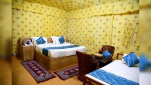 - une chambre avec 2 lits, des chaises et du papier peint jaune dans l'établissement Hotel Sun Heaven Senerity, à Jaisalmer