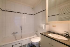 een witte badkamer met een toilet en een wastafel bij 4e verdiep appartement met zeezicht in Knokke in Knokke-Heist