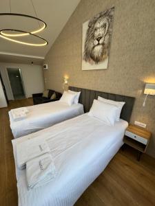 twee bedden in een hotelkamer met een leeuwenfoto aan de muur bij Triangle Rooms in Raška