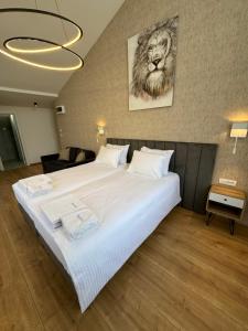 een slaapkamer met een groot wit bed met een foto van een leeuw bij Triangle Rooms in Raška