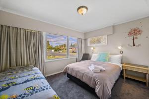 a bedroom with two beds and a large window at Red Brick Cottage-First choice for families in Rotorua