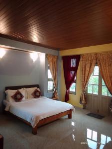 a bedroom with a large bed with a wooden ceiling at LaMansion Inn in Cherrapunji