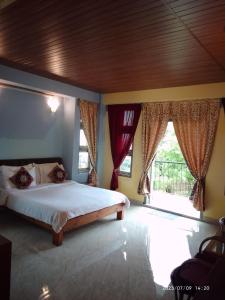 a bedroom with a bed and a large window at LaMansion Inn in Cherrapunji
