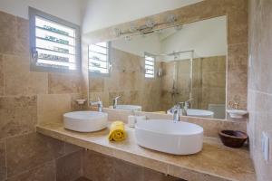 ein Badezimmer mit zwei Waschbecken und einem großen Spiegel in der Unterkunft Villa Saint Alban by Habitation Saint Charles in Petit-Bourg