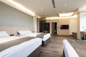 白河区にあるHoya Hot Springs Resort, Guanzilingのベッド3台、薄型テレビが備わるホテルルームです。