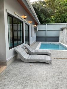 een zwembad met 2 ligstoelen naast een huis bij Aonang Peace Pool Villa in Ban Khlong Haeng