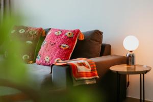 a couch with a pink pillow and a table with a lamp at Cozy 1 BR in Dubai Marina in Dubai