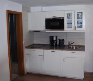 a kitchen with white cabinets and a sink and a microwave at Gästehaus Sonnenbichl in Reit im Winkl