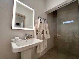 La salle de bains est pourvue d'un lavabo, d'un miroir et d'une douche. dans l'établissement Perla Coco Jacuzzi Suites, à La Canée