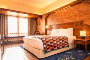 a bedroom with a large bed and a brick wall at Hotel Yak & Yeti in Kathmandu