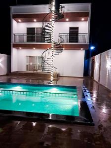 a swimming pool in front of a building with a spiral staircase at P Villa in Devanahalli-Bangalore