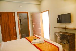 a hotel room with a bed and a television at FabHotel Home Tree Service Apartment Kolathur in Chennai