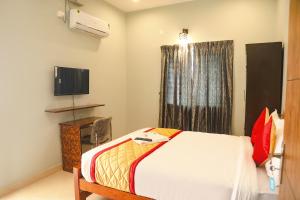 a bedroom with a bed and a tv and a window at FabHotel Home Tree Service Apartment Kolathur in Chennai