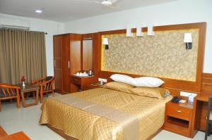 a bedroom with a bed and a table and chairs at Kallada Mamatha Motels in Kunnamkulam