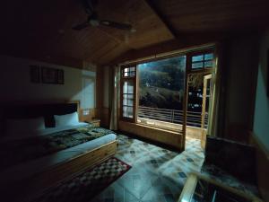 ein Schlafzimmer mit einem Bett und einem großen Fenster in der Unterkunft Hotel Saryal , Kullu in Kulu