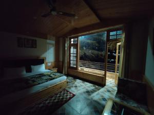 a bedroom with a bed and a large window at Hotel Saryal , Kullu in Kulu