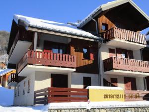 un gran edificio con balcones de madera en la nieve en Residence Les Choseaux - 2 Pièces pour 6 Personnes 764, en Valloire