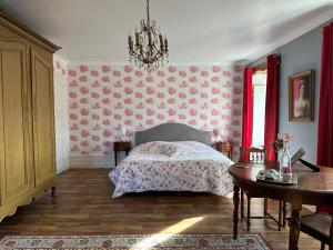 una camera con letto, tavolo e lampadario a braccio di Château de la Preuille Bed & Breakfast a Montaigu-Vendée