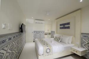 a white bedroom with a large bed and a tv at Jaipur Bungalow in Jaipur
