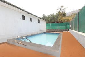 una piscina sul lato di un edificio di OYO A J Mountain View Cottage a Lonavala