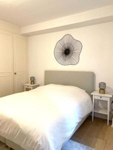 402* City center in Montreux في مونترو: غرفة نوم بسرير ابيض ومروحة على الحائط