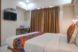 a bedroom with a bed and a desk and a television at FabHotel Emersion Residency in Pune