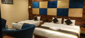 una habitación de hotel con 2 camas y una silla azul en Poddar Residency, en Kuch Bihār