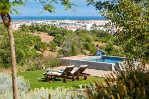 a woman is standing next to a swimming pool at Monte Do Alamo - Turismo Rural in Tavira