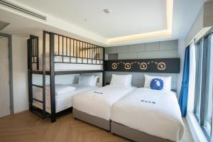 Kokotel Chiang Rai Airport Suites في Ban Prong Phra Bat Nok: غرفة نوم بسريرين وسرير بطابقين