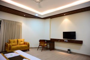 a living room with a tv and a chair and a desk at Unnati Stay Inn in Bijāpur