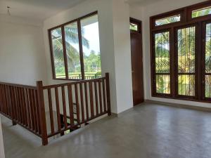 an empty room with a staircase and large windows at Villa paddy feild in Hiripitiya