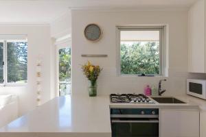 a kitchen with a stove and a clock on the wall at Manly Beach Haven w Parking in Sydney