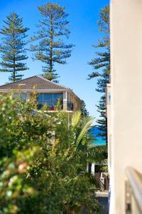 a house with two trees in front of a building at Manly Beach Haven w Parking in Sydney