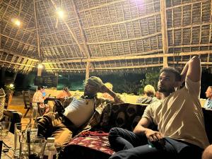 a group of people sitting on couches under a roof at Sazani Beach Lodge and Tidal Lounge in Nungwi