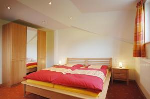 a bedroom with a large bed with red sheets at Pension Kilger in Mauth