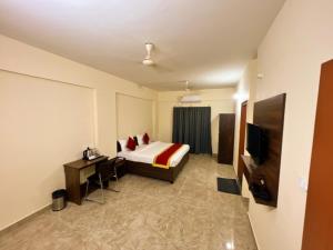 um quarto de hotel com uma cama e uma televisão em Sai Manyata Inn, Bangalore em Bangalore