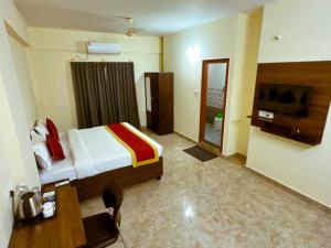 um quarto com uma cama, uma secretária e uma televisão em Sai Manyata Inn, Bangalore em Bangalore